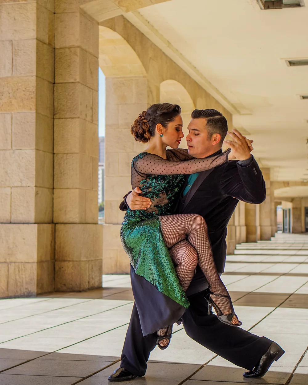 Et tangopar midt i en drejning, kvinden i en grøn kjole med pailletter (repræsentativt fotografi af argentinsk/uruguayansk tango, ikke Primuseum selv)